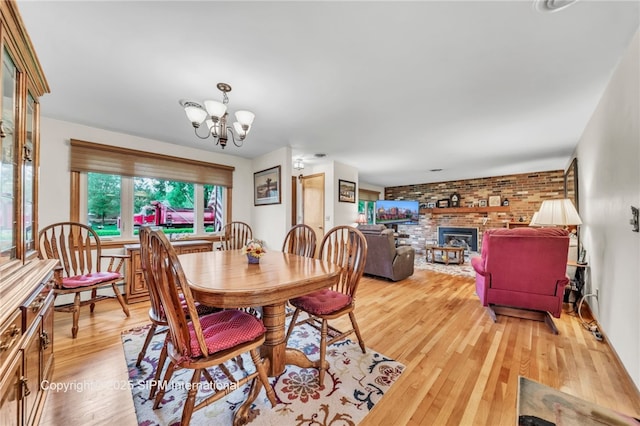 393 Bauman Rd, Amherst, NY 14221 - dining space with wood finished floors, a chandelier, brick wall, and a brick fireplace