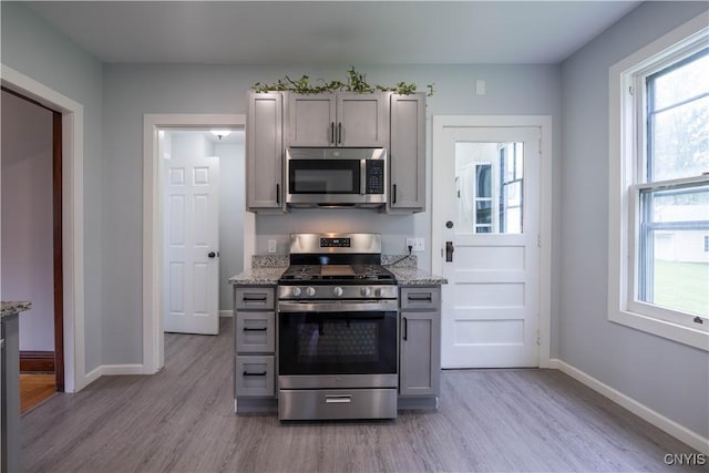 611 Turin St, Rome-Inside, NY 13440 - kitchen featuring stainless steel appliances, light wood finished floors, gray cabinets, baseboards, and light stone counters