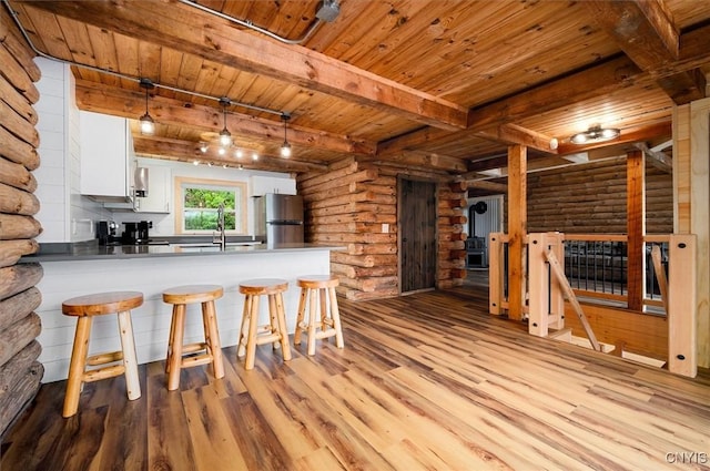 1159 Hunt Rd, Forestport, NY 13494 - kitchen with light wood-type flooring, wood ceiling with exposed beams, freestanding refrigerator, log walls, and a peninsula