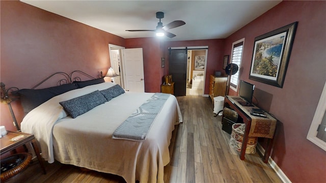 7404 Bonney Hill Rd, Hamilton, NY 13346 - bedroom with a barn door, wood finished floors, and a ceiling fan
