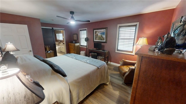 7404 Bonney Hill Rd, Hamilton, NY 13346 - bedroom featuring a barn door, wood finished floors, baseboards, and ceiling fan