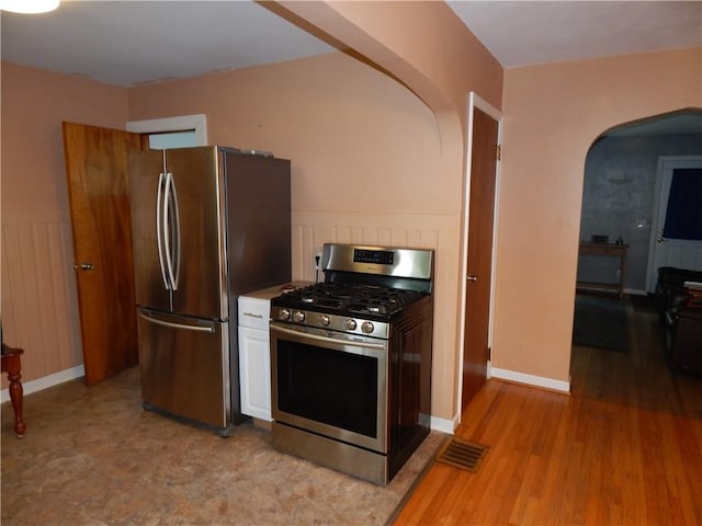 908 W 2nd St, Elmira, NY 14905 - kitchen with appliances with stainless steel finishes, arched walkways, white cabinets, light wood finished floors, and baseboards