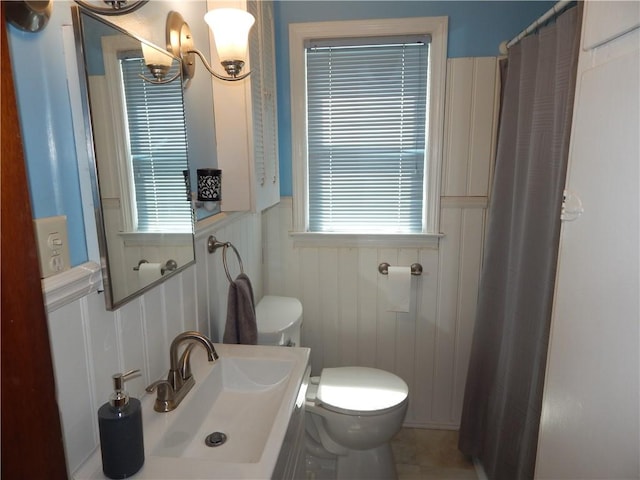 908 W 2nd St, Elmira, NY 14905 - full bathroom featuring a sink, toilet, wainscoting, curtained shower, and a decorative wall