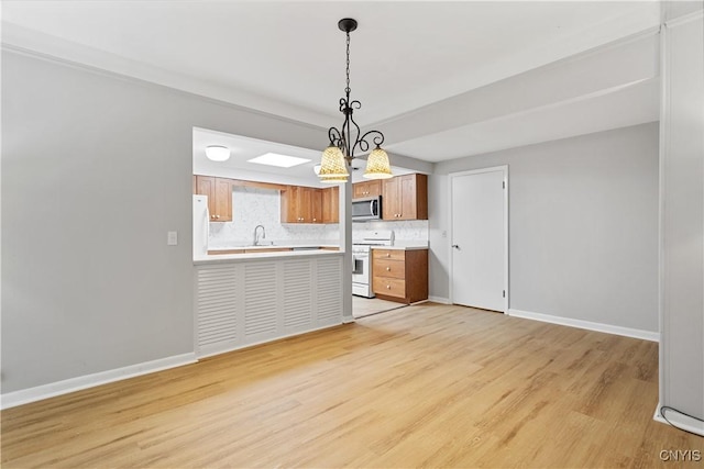 24 The Orch, Manlius, NY 13066 - kitchen featuring white appliances, light countertops, light wood-style flooring, brown cabinets, and baseboards