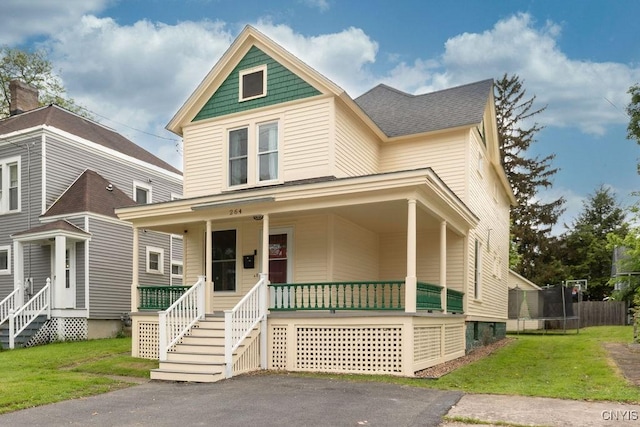 264 S 5th St, Fulton, NY 13069 - view of front of house with a trampoline, covered porch, a front lawn, and a shingled roof