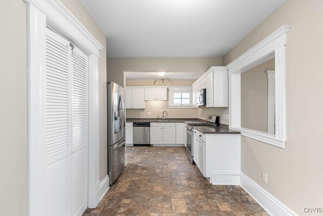 264 S 5th St, Fulton, NY 13069 - kitchen featuring stainless steel appliances, a sink, dark countertops, stone finish flooring, and baseboards