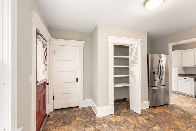 264 S 5th St, Fulton, NY 13069 - kitchen with stainless steel fridge, stone finish floors, white cabinetry, baseboards, and dark countertops
