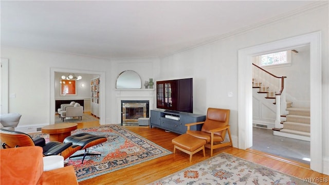 80 Lake St, Urbana, NY 14840 - living room with stairs, wood finished floors, a chandelier, ornamental molding, and a glass covered fireplace