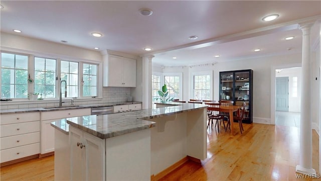 80 Lake St, Urbana, NY 14840 - kitchen featuring a sink, decorative columns, light stone countertops, a center island, and decorative backsplash