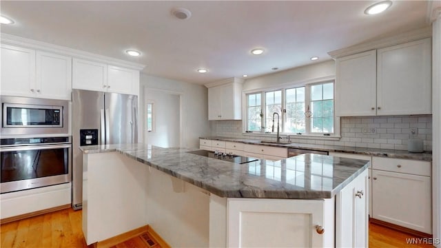 80 Lake St, Urbana, NY 14840 - kitchen featuring appliances with stainless steel finishes, a sink, backsplash, light stone countertops, and light wood-style floors