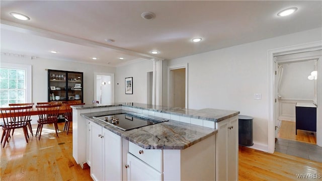 80 Lake St, Urbana, NY 14840 - kitchen with black electric stovetop, light wood finished floors, white cabinets, a kitchen island, and light stone countertops