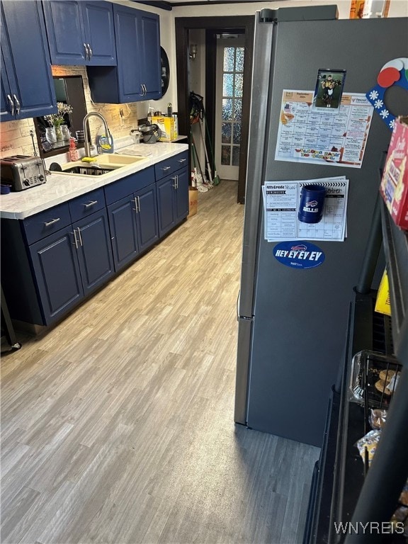 125 Spaulding St, Buffalo, NY 14220 - kitchen with blue cabinets, freestanding refrigerator, a sink, light wood-style flooring, and light countertops