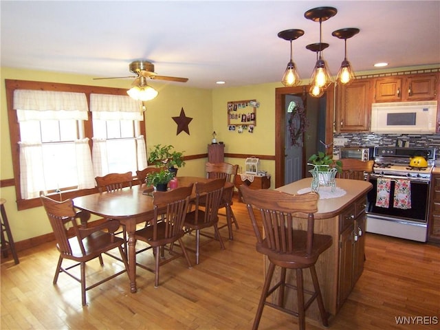 8330 Greiner Rd, Clarence, NY 14221 - kitchen with white appliances, a ceiling fan, light wood finished floors, a kitchen island, and decorative backsplash