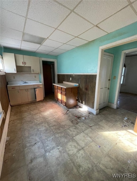 500 Massachusetts Ave, Buffalo, NY 14213 - kitchen with a drop ceiling, wooden walls, a wainscoted wall, light countertops, and a sink
