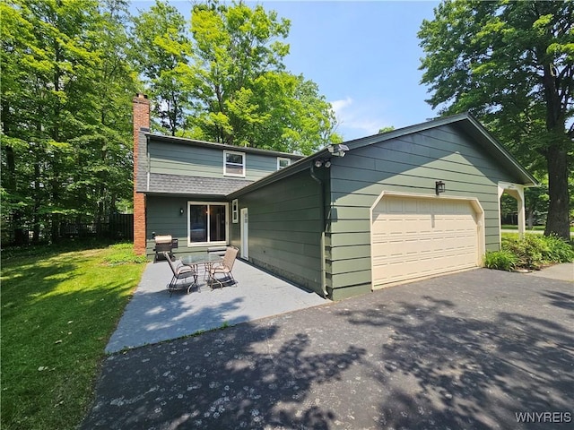 7066 E Ln, Boston, NY 14057 - view of front of home featuring a garage, a chimney, asphalt driveway, and a patio area