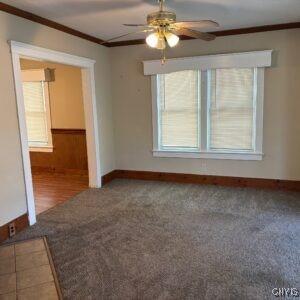 214 W 3rd St S, Fulton, NY 13069 - unfurnished room featuring crown molding, ceiling fan, baseboards, and carpet