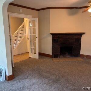 214 W 3rd St S, Fulton, NY 13069 - unfurnished living room with stairway, ceiling fan, carpet flooring, a fireplace, and arched walkways