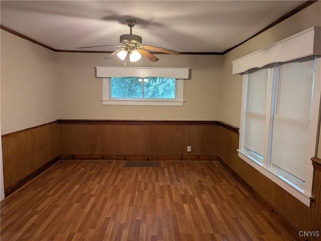 214 W 3rd St S, Fulton, NY 13069 - spare room featuring wood finished floors, wood walls, wainscoting, ornamental molding, and a ceiling fan