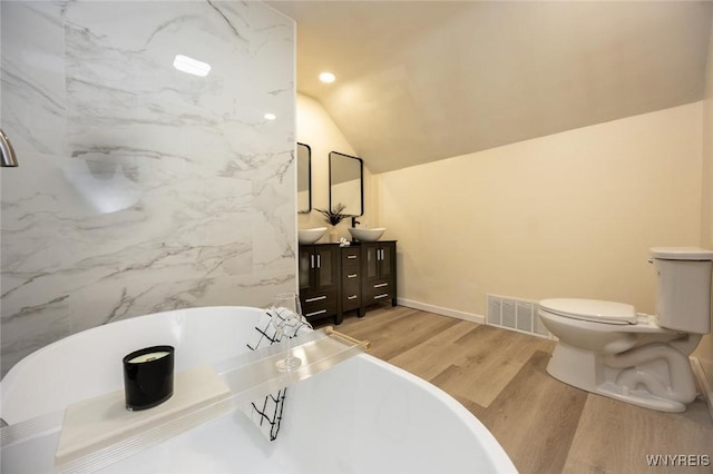 70 Minard St, Lockport-City, NY 14094 - full bathroom with wood finished floors, double vanity, a soaking tub, toilet, and vaulted ceiling