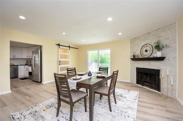 70 Minard St, Lockport-City, NY 14094 - dining space with light wood finished floors, a barn door, a fireplace, baseboards, and recessed lighting