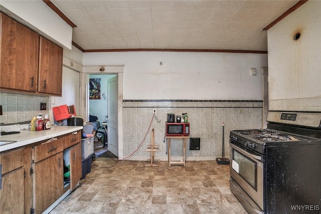110 Saint Louis Ave, Buffalo, NY 14211 - kitchen featuring stainless steel range with gas stovetop, ornamental molding, brown cabinets, light countertops, and tile walls