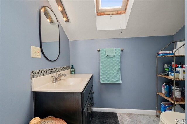 408 Elm St, Manlius, NY 13066 - bathroom featuring a skylight, vanity, toilet, lofted ceiling, and baseboards
