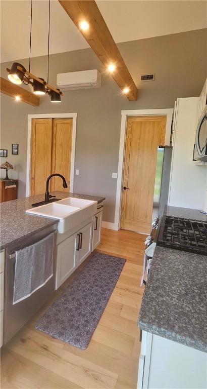 2185 Hog Mountain Rd, Middletown, NY 12455 - kitchen with an AC wall unit, a sink, light wood-style flooring, white cabinets, and gas stove