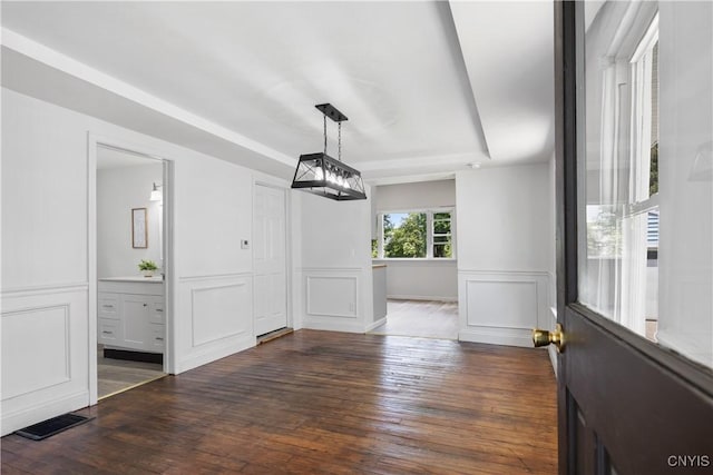 220 W Elm St, Oneida-Inside, NY 13421 - unfurnished dining area featuring a tray ceiling, a decorative wall, dark wood finished floors, and a wainscoted wall