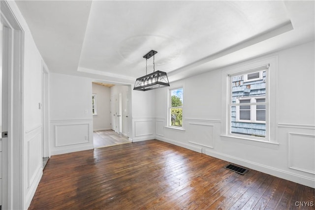 220 W Elm St, Oneida-Inside, NY 13421 - unfurnished dining area featuring a tray ceiling, hardwood / wood-style floors, and a decorative wall