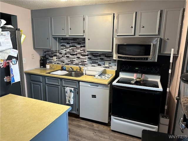6954 Academy Ln, Lockport-Town, NY 14094 - kitchen featuring appliances with stainless steel finishes, a sink, decorative backsplash, wood finished floors, and light countertops