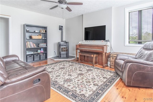 24401 Cheever Rd, Pamelia, NY 13601 - living room with ceiling fan, a textured ceiling, light wood-style floors, and a wood stove