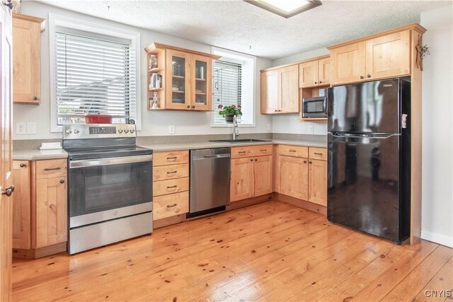 24401 Cheever Rd, Pamelia, NY 13601 - kitchen with stainless steel appliances, light brown cabinets, a sink, light wood finished floors, and a textured ceiling