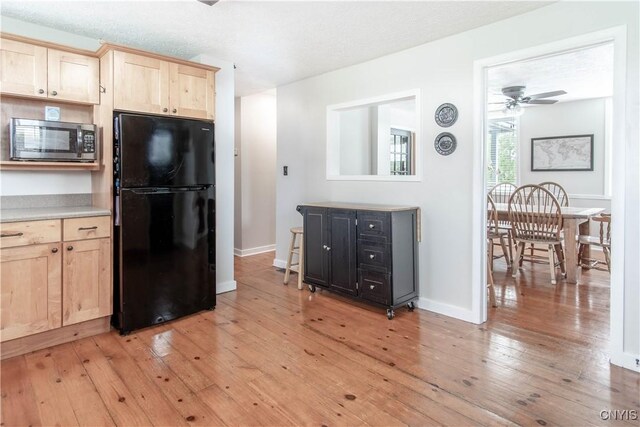 24401 Cheever Rd, Pamelia, NY 13601 - kitchen with freestanding refrigerator, stainless steel microwave, light brown cabinetry, and light wood finished floors