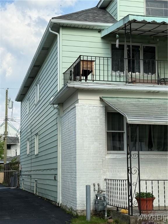 189 Lovering Ave, Buffalo, NY 14216 - view of side of home featuring a balcony, roof with shingles, and brick siding