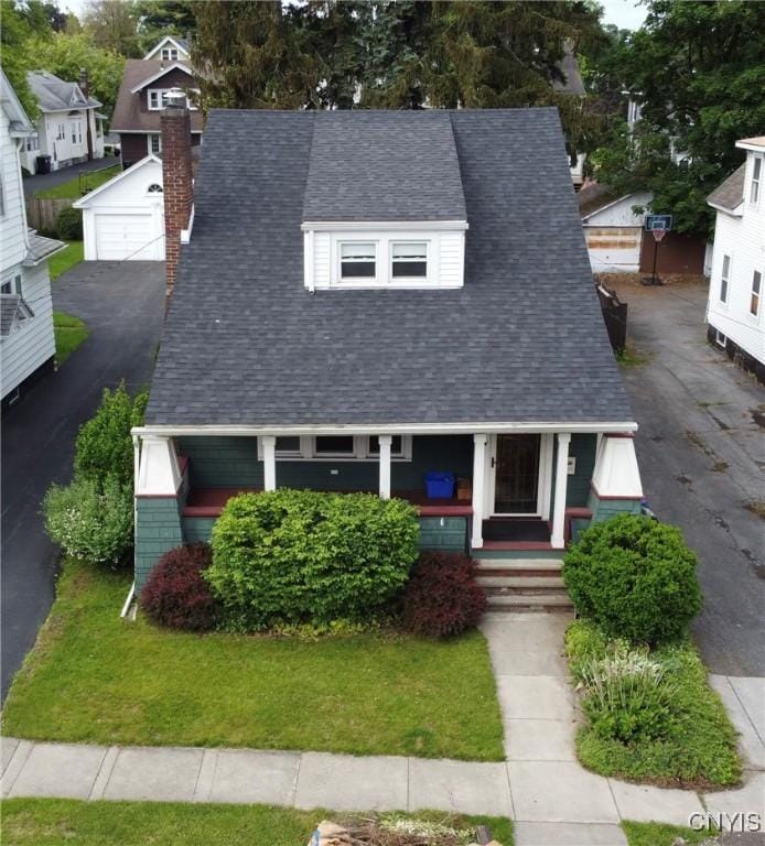 175 Kuhl Ave, Syracuse, NY 13208 - view of front of house featuring a porch, a chimney, a shingled roof, a detached garage, and an outbuilding