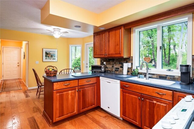 41 Pond Valley Cir, Penfield, NY 14526 - kitchen featuring dishwasher, a sink, a peninsula, brown cabinetry, and tasteful backsplash