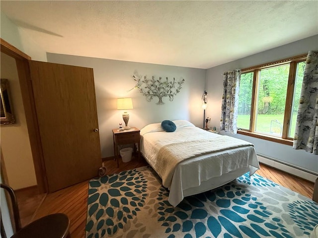 1476 Grange Hall Rd, Junius, NY 14532 - bedroom with baseboard heating, wood finished floors, and a textured ceiling