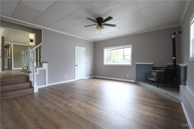22245 Patricia Dr, Le Ray, NY 13601 - unfurnished living room featuring ceiling fan, a wood stove, stairway, wood finished floors, and ornamental molding