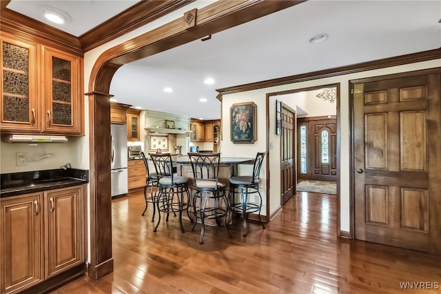 29 Brunck Rd, Lancaster, NY 14086 - kitchen featuring freestanding refrigerator, crown molding, dark wood finished floors, glass insert cabinets, and arched walkways