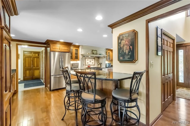 29 Brunck Rd, Lancaster, NY 14086 - kitchen featuring stainless steel fridge, a kitchen bar, light wood-type flooring, glass insert cabinets, and ornamental molding