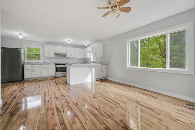 10610 State Route 7, Worcester, NY 12149 - kitchen with freestanding refrigerator, stainless steel range with electric stovetop, under cabinet range hood, light wood finished floors, and white cabinetry