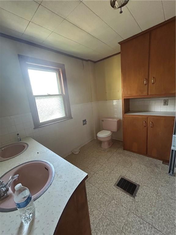 1227 Lake St, Elmira-City, NY 14901 - bathroom with double vanity, a wainscoted wall, toilet, and tile walls