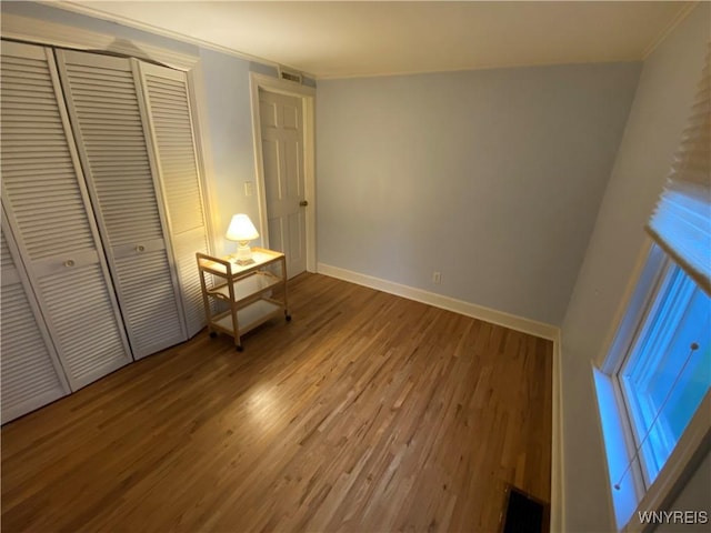 5780 Sheridan Dr, Amherst, NY 14221 - unfurnished bedroom featuring wood finished floors, crown molding, baseboards, and a closet