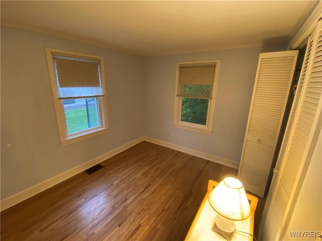 5780 Sheridan Dr, Amherst, NY 14221 - unfurnished bedroom featuring dark wood-type flooring, baseboards, a closet, and crown molding
