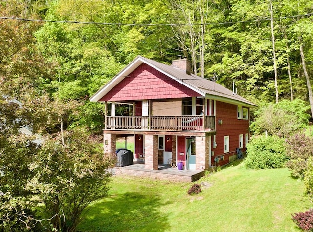 25 Woodside Ave, Oneonta-City, NY 13820 - rear view of property featuring a chimney, a patio area, a wooded view, and a yard