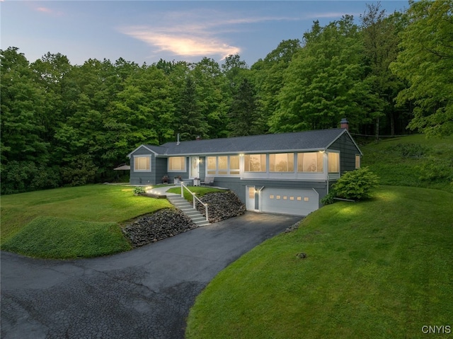 11245 Bell Hill Rd, Deerfield, NY 13502 - view of front of home with asphalt driveway, a garage, and a forest view