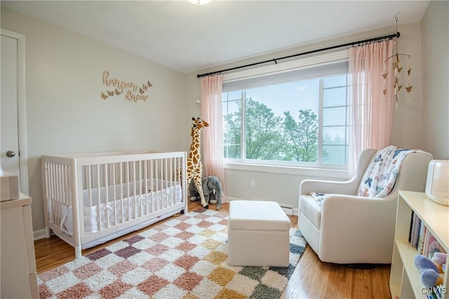11245 Bell Hill Rd, Deerfield, NY 13502 - bedroom featuring wood finished floors, a crib, baseboards, and a baseboard radiator