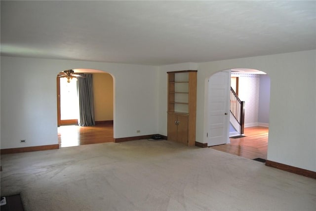 202 Birch St, Kane Boro, PA 16735 - carpeted empty room featuring arched walkways, stairway, and a ceiling fan