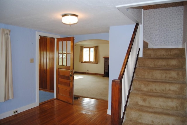 202 Birch St, Kane Boro, PA 16735 - staircase with arched walkways, wood finished floors, carpet flooring, and a brick fireplace