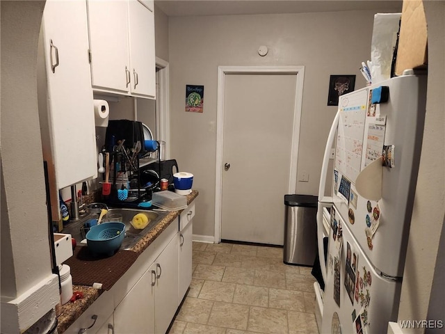 237 Tremont St, North Tonawanda, NY 14120 - kitchen with freestanding refrigerator, white cabinetry, dark countertops, stone finish floors, and a sink